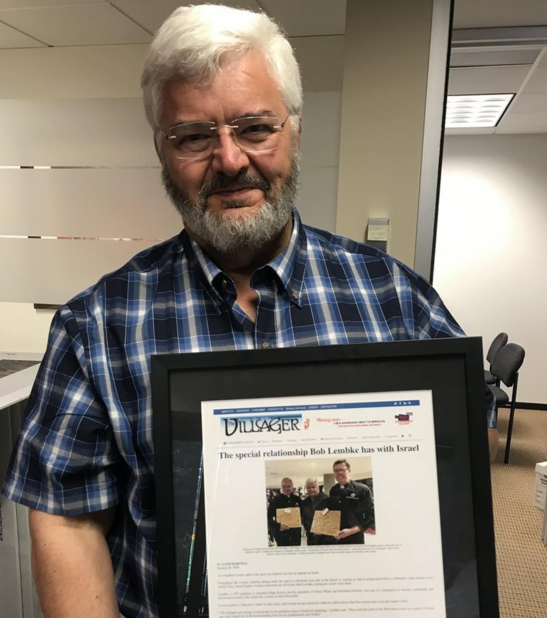 Bob Lembke holds a framed article about his trip to Israel that he received from Mike Dino.