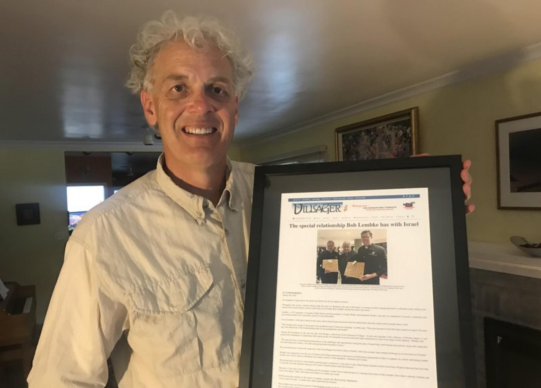 Mike Dino holds a framed article about Bob Lembke. 