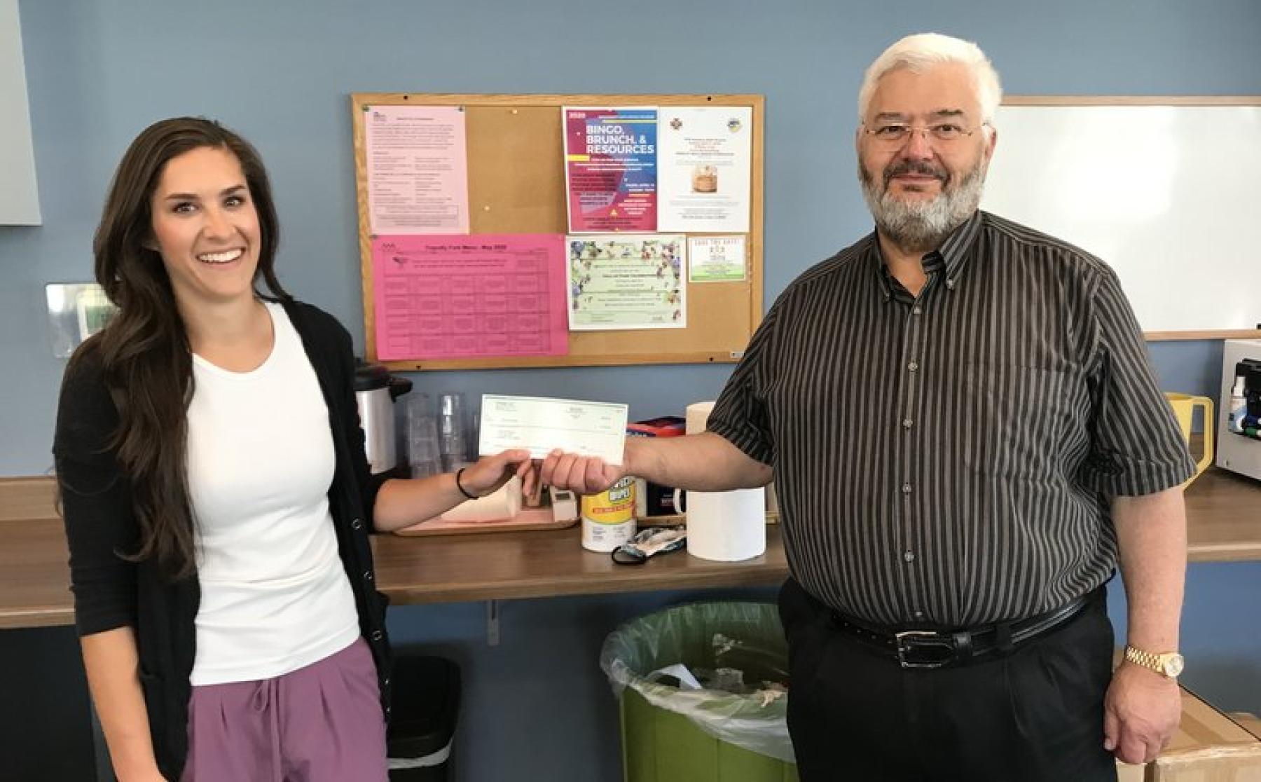 Bob Lembke, the owner of 70 Ranch, hands a check for $5,000 to Kayla Guerin who works for Kersey, for the town's seniors program. 